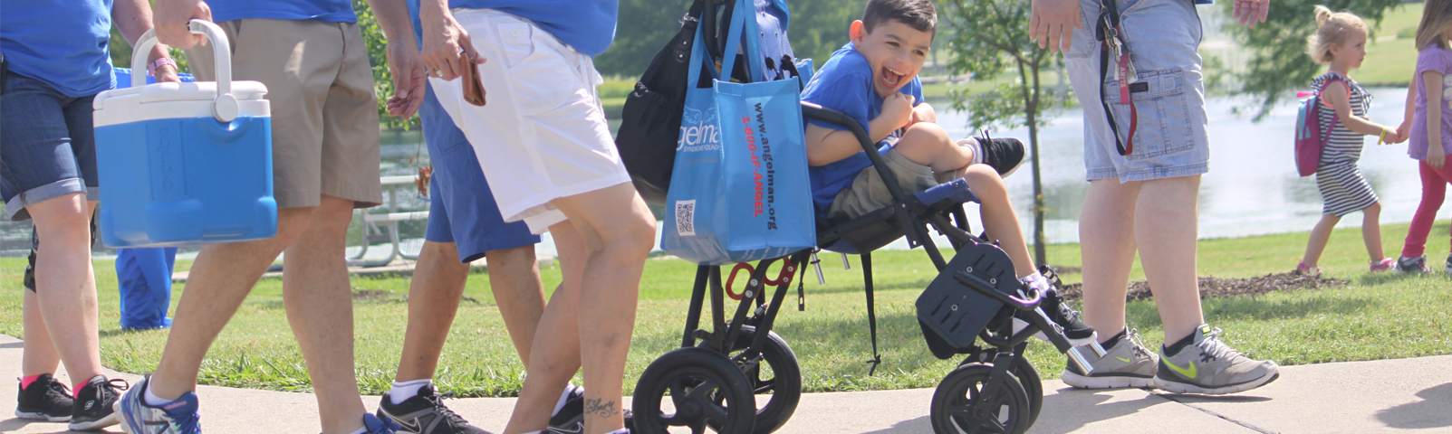 People at an ASF Walk and a boy with Angelman syndrome in a stroller laughing