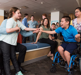 Two children with Angelman syndrome reaching out to touch hands