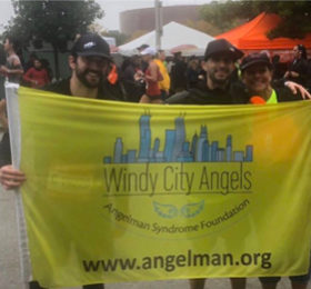 Two marathon runners holding a flag that says Windy City Angels