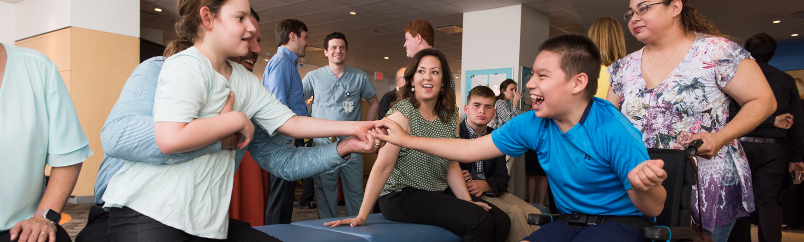 Two individuals with Angelman syndrome reaching out to touch hands